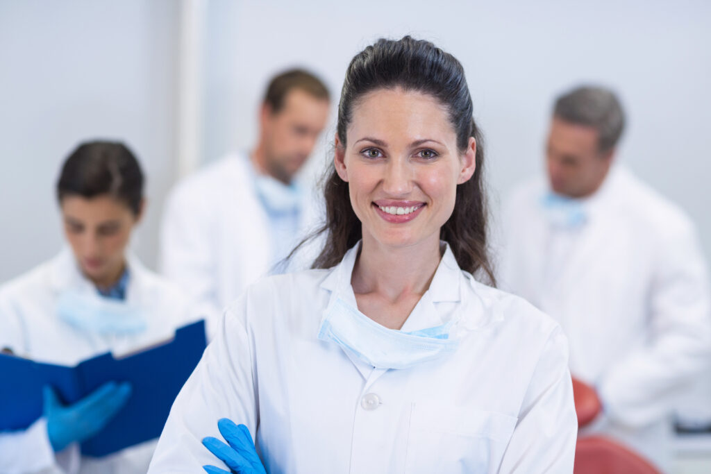 Portrait Of Smiling Dentist Standing With Arms Crossed In Dental Clinic